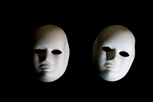 Two minimal plain white masks on a black background
