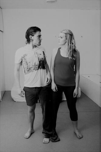 Two participants standing each with one leg through the same leg of a pair of trousers