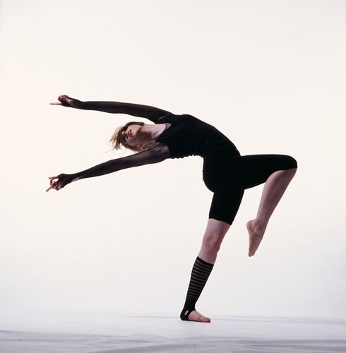 A figure all in black on a white backdrop in movement
