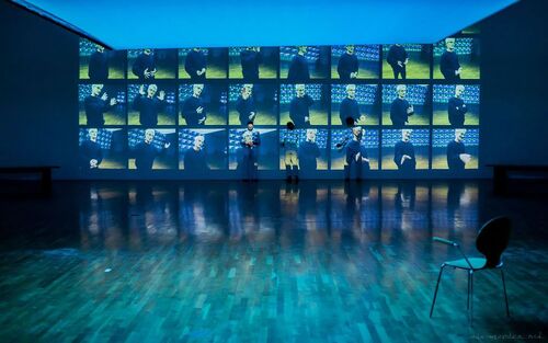 Three dancers in the distance in movement against a wall cast with projections