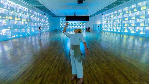 Justine Cooper in movement with a gallery space stretching out behind her