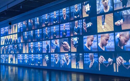 Projections of many still shots of a figure in a grid cast on a gallery wall