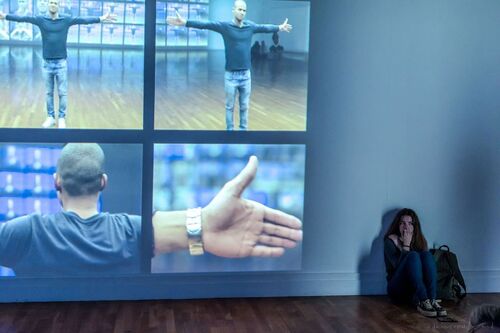 An audience member sitting on the floor beside projections on the wall