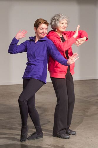 Two participants in bright colours moving back to back