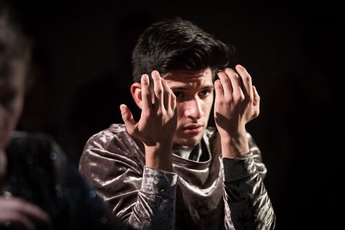 A close up of a participant with hands to the sides of his face in a silver costume
