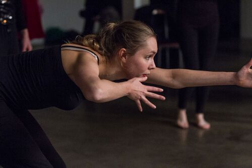A participant seen in side profile in movement reaching her arm out