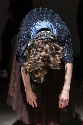 A figure standing with their torso folded over