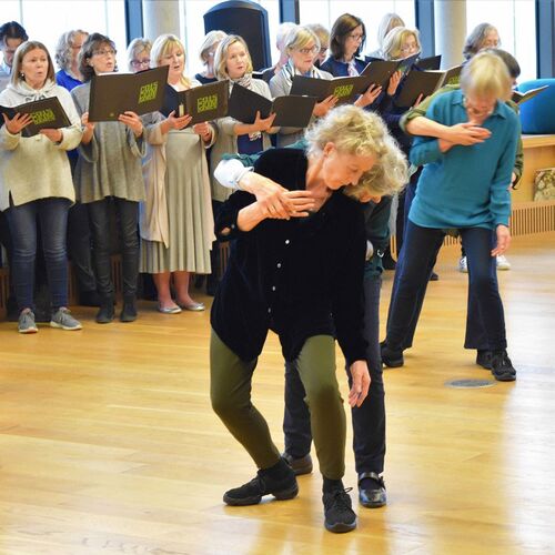 Older participants in movement in duets with others standing behind singing