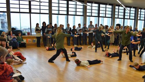 Young and older participants in movement with the children lying stretched on the floor