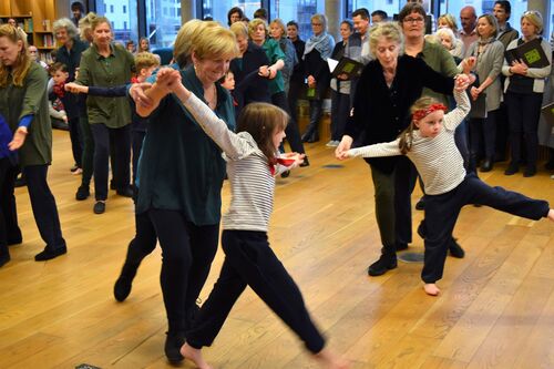 Young and older participants dancing together in an open library space