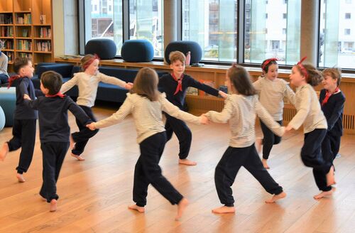 Young participants in movement in a circle holding hands