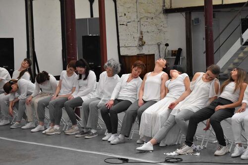 An ensemble of participants sitting in a line as though asleep