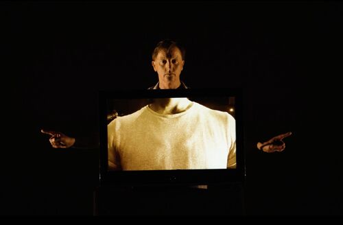 David Bolger's head and hands emerging from the side of a screen showing a torso