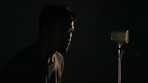 Donking Rongavilla in dark side profile in front of a microphone