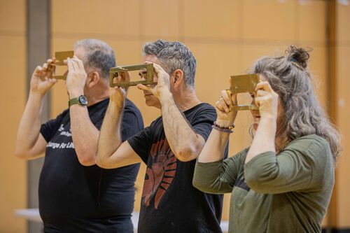 Three figures looking through letterboxes they hold in front of their faces