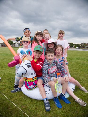A group of children sitting on a pool inflatable ring on a football pitch