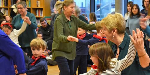 Young and older participants dancing together in a library space