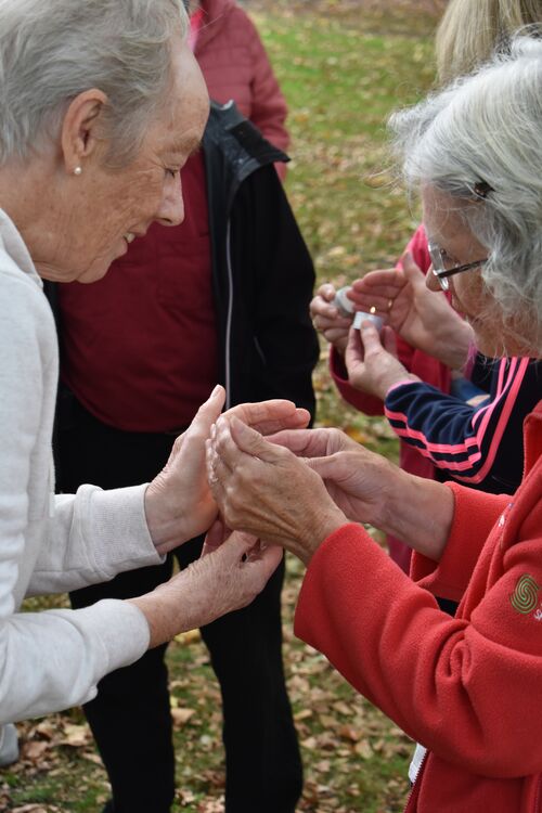 Two participants sheltering a tea-light while lighting it in the park