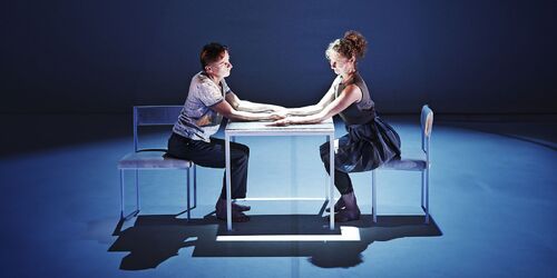 Two figures seated opposite each other at a table