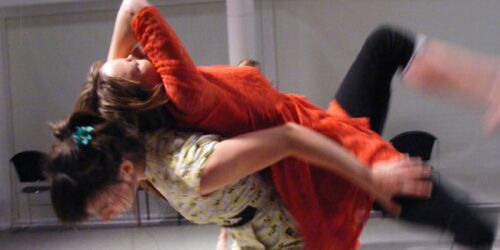 Two participants in movement with one in motion across the others back