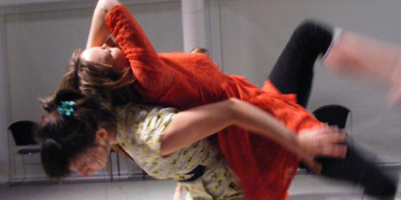 Two participants in movement with one in motion across the others back