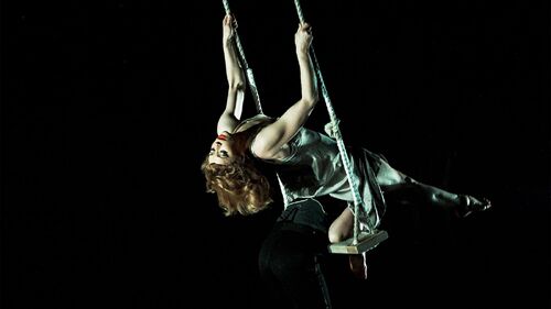 A dancer leaning back on a swing