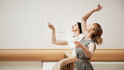 Two dancers at a balcony edge in movement