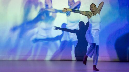 A dancer in movement with projections of her movement cast behind