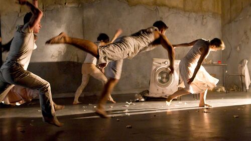Four dancers in movement towards a source of light