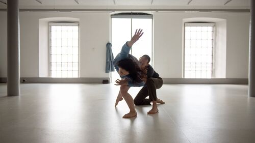 Two dancers in movement in a bare space