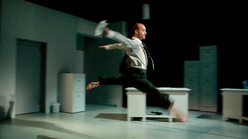 A dancer mid leap in an office set