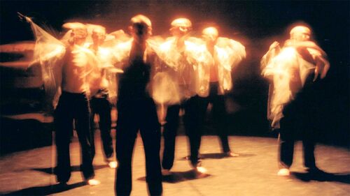 An ensemble of dancers in movement, blurred in motion