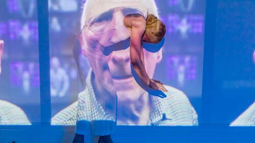 A figure in movement with the image of a persons face projected on her