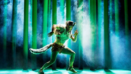 A figure costumed as a wolf in movement centre stage