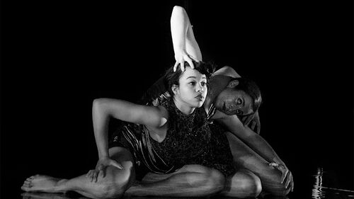 Two figures on the floor with limbs entwined