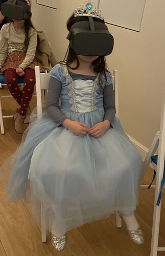 A young girl in VR goggles seating on the chair