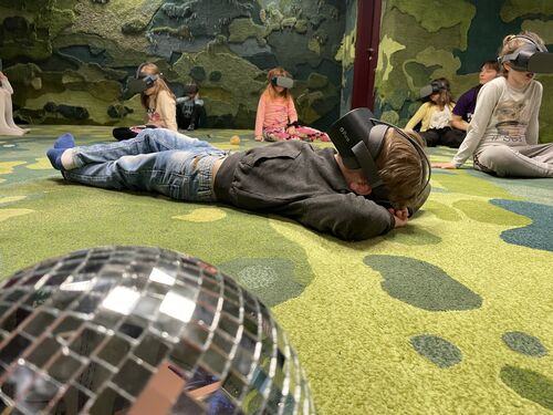 A young boy in VR goggles lying on the floor