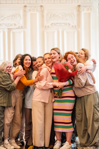 The dancers are hugging each other and the choreographer on the stage