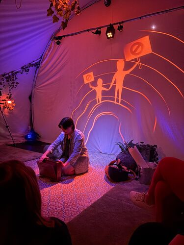 A woman sitting on the floor with the projections of the protest on the wall behind her