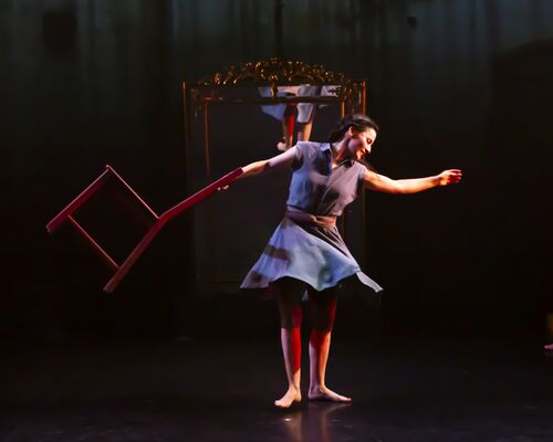 A girl spinning with a red chair in her hand