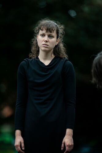 A woman in black standing in a static position