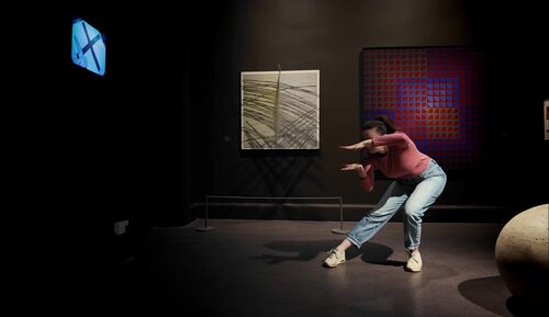 A dancer in a movement against the backdrop of the artworks