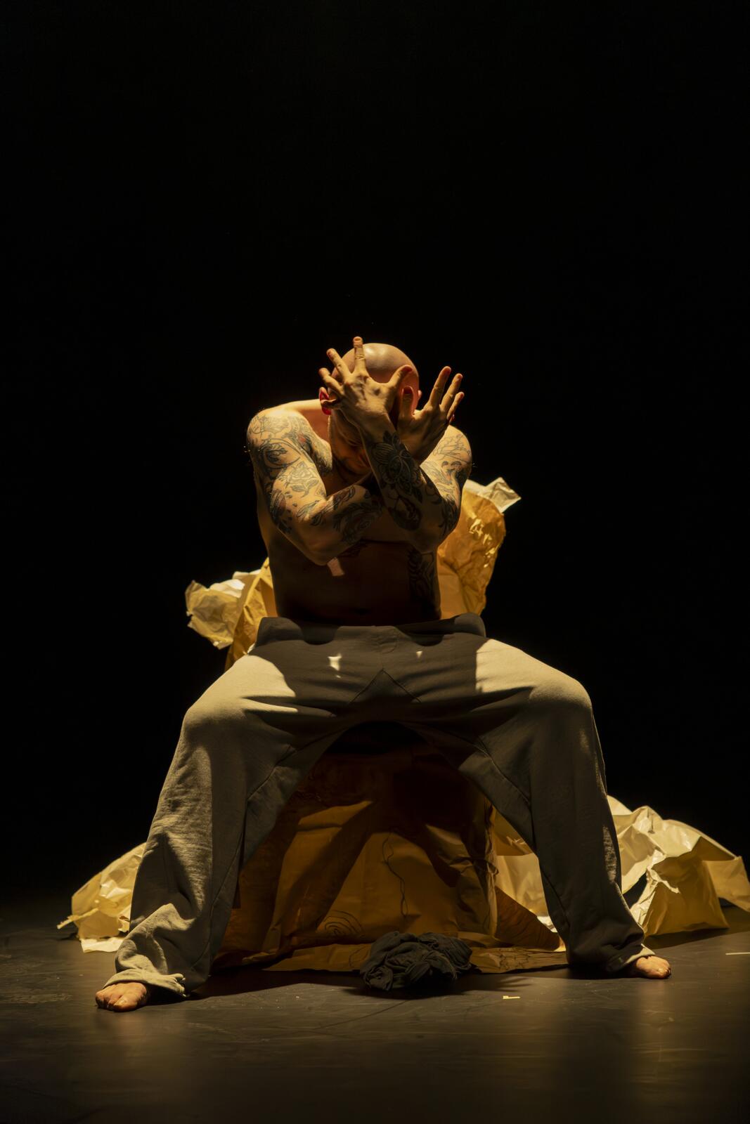 A man sitting on a chair with his hands crossed and covering his face